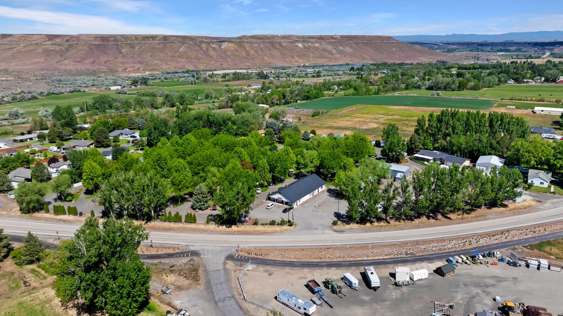Aerial view of Hagerman RV Village's tree-shaded sites along Highway 30, with the Snake River canyon rim beyond